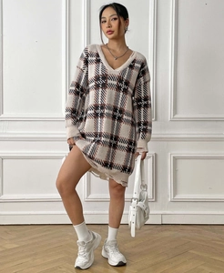Detail of oversized V-neck sweater dress featuring plaid pattern and distressed frayed hem