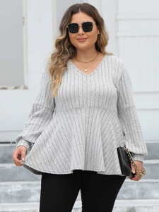Detail of grey V-neck peplum top featuring textured ribbed knit fabric and long sleeves