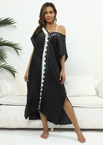 Detalle de vestido playero negro con bordado de ganchillo blanco y abertura lateral