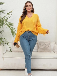 Bright yellow V-neck knit sweater with trendy fringe detailing and casual blue jeans