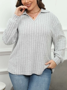 Detail of light grey ribbed knit fabric texture on women's V-neck polo long sleeve top