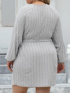 Rear view of grey ribbed knit long-sleeved dress with waist tie on stone stairs