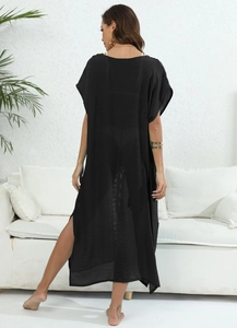 Detalle de un vestido playero negro transparente con abertura lateral alta y largo maxi