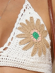 Detailed macro view of handmade crochet bikini top with colorful floral embroidery detail