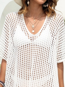 Detail of white crochet beach cover-up featuring deep V-neck and hollow knit texture