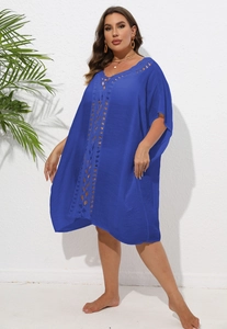 Détail des motifs en crochet ajouré sur une robe de plage bleue ample de style vacances