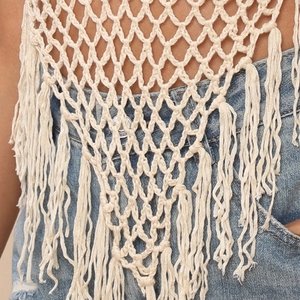 Close-up of bohemian crochet mesh texture and long fringe tassels on beach cover-up