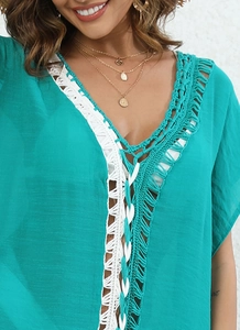 Detailed view of deep V-neckline with white crochet lace on teal beach cover-up