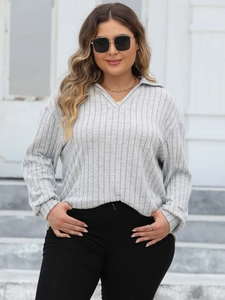 Detail of light grey polo neck knit sweater showing vertical ribbed texture and v-neckline