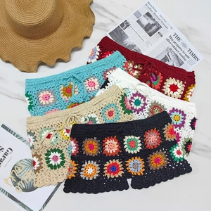 Detail of five colorful crochet beach shorts with floral patterns and scalloped edges