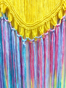 Détail du macramé mural tissé à la main avec lune jaune et franges multicolores