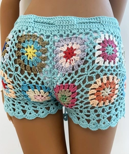 Detailed macro view of handmade crochet stitches and colorful floral patchwork on blue shorts