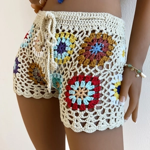 Close-up of handmade crochet beach shorts featuring colorful floral motifs and drawstring