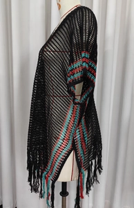 Détail de robe de plage en crochet avec motifs géométriques et longues franges tricolores