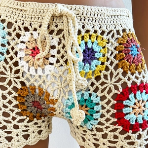 Detail of bohemian handmade granny square crochet beach shorts with colorful floral patterns
