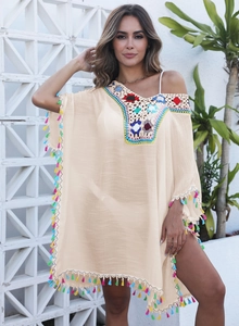 Détail du décolleté au crochet coloré et franges vives sur une robe de plage bohème beige