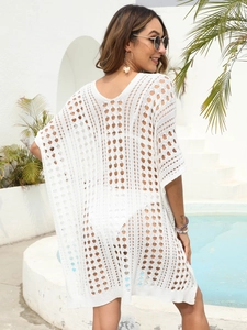 Detail of white crochet knit beach cover-up with intricate hollow-out floral patterns
