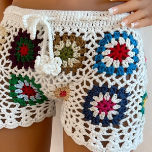 Close-up of handmade crochet beach shorts featuring colorful granny square floral patterns