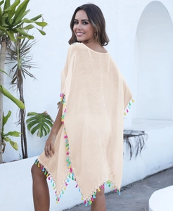 Détail de franges à pompons colorés sur une robe de plage bohème beige col en V