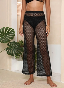 Gros plan sur la dentelle au crochet noire de ce pantalon de plage évasé ajouré