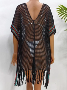 Détail d'une robe de plage noire au crochet avec rayures colorées et longues franges
