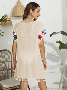 Vue détaillée des fleurs au crochet colorées et des franges sur un cache-maillot beige