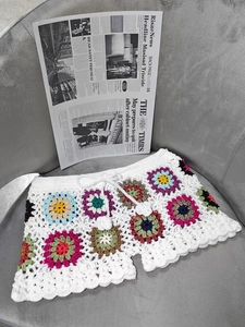 Detail of handmade crochet beach shorts featuring multi-colored granny square patterns