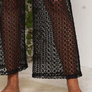 Gros plan détaillé montrant les motifs de dentelle ajourée sur ce pantalon de plage noir