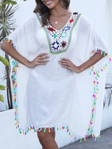 Détail du col en crochet coloré et franges vives sur la robe de plage blanche