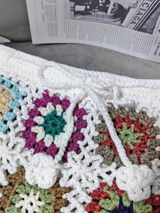 Detail of handmade crochet beach shorts with colorful granny squares and floral drawstring