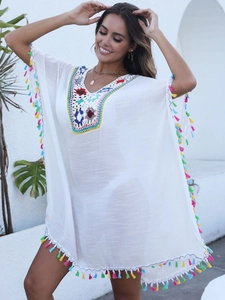 Détail du décolleté en crochet coloré et pompons à franges sur un cache-maillot blanc
