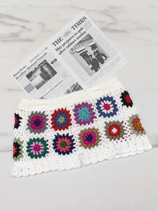 Handmade granny square crochet beach shorts with colorful floral patchwork on white knit