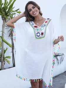 Détail de l'encolure en crochet coloré et franges sur une robe de plage blanche légère