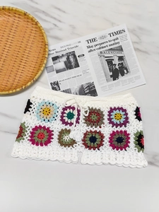 Detail of handmade crochet beach shorts featuring colorful granny square floral patterns