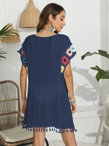 Détail d'une robe de plage bleu foncé avec fleurs au crochet colorées et ourlet à franges