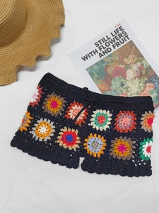 Macro detail of Bohemian crochet shorts featuring colorful floral knit patterns and tassels