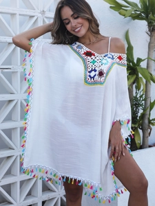 Détail de robe de plage blanche avec broderies crochetées colorées et pompons bohèmes
