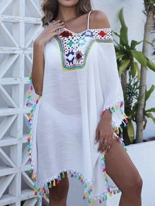 Détail macro de la broderie florale au crochet et franges colorées sur robe de plage blanche