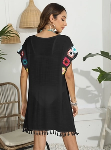 Détail de fleurs au crochet colorées et de franges sur un cache-maillot noir