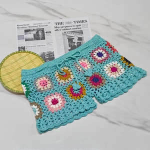 Detail of crochet beach shorts with colorful 3D floral patterns and waist drawstring