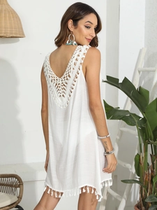 Détail d'un cache-maillot bohème blanc au crochet avec des pompons à franges