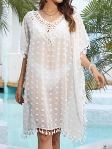 Détail de la tunique de plage blanche avec dentelle crochetée et pompons au bord