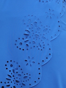 Detail of blue beach dress with elegant floral eyelet embroidery and smooth fabric texture