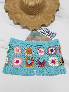 Detail of crochet beach shorts with colorful floral patterns and a side drawstring tie