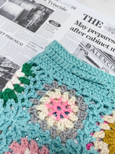Detailed macro view of colorful granny square crochet patterns on beach shorts fabric