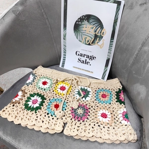 Detail of handmade crochet beach shorts with colorful granny square patterns and drawstring