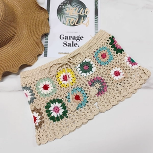 Detail view of handmade crochet beach shorts with colorful floral patterns and drawstring