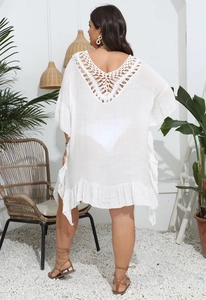 Detail of V-shaped crochet hollow pattern and ruffled hem on white beach cover-up