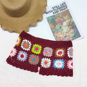 Detail of crochet beach shorts featuring multi-color granny square patterns and wavy edges