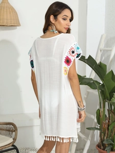 Détail de la tunique de plage blanche avec manches en crochet coloré et bordures à franges